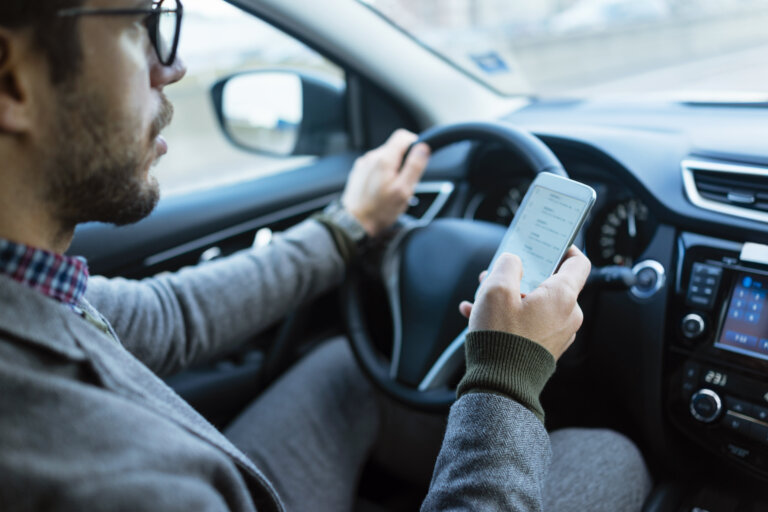 man holding cellphone while driving